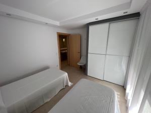 a white bedroom with a bed and a sliding glass door at Apartamentos Flamingo Hills in Benitachell