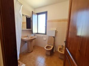 a bathroom with a toilet and a sink at VILLA TO' in Àrbatax