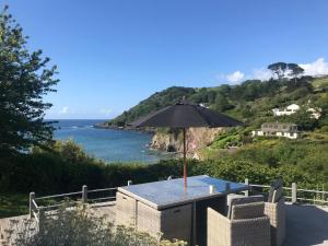 a table with an umbrella and chairs and the ocean at Beach Front House with Stunning Sea Views and Free Use of a Local Indoor Pool in Talland