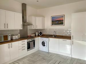 a kitchen with white cabinets and a dishwasher at The Place - Lytham in Lytham St Annes