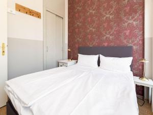 ein Schlafzimmer mit einem weißen Bett und einer roten Wand in der Unterkunft Villa Amelia, App. 06 in Heringsdorf