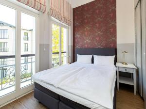 ein Schlafzimmer mit einem großen weißen Bett und Fenstern in der Unterkunft Villa Amelia, App. 07 in Heringsdorf