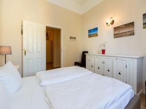 1 Schlafzimmer mit 2 weißen Betten und einem Schrank in der Unterkunft Villa Arcadia, App. 05 in Heringsdorf