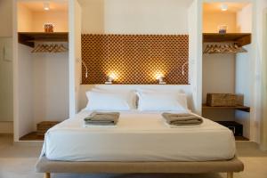 - une chambre avec un lit blanc et 2 serviettes dans l'établissement Pozzo Traverso Casale, à Leporano Marina