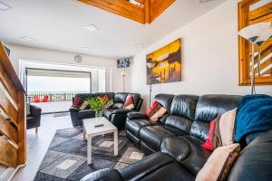 a living room with a leather couch and a table at Family Beachfront Bliss Sleeps 10 in Pevensey