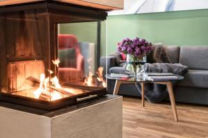 a fireplace in a living room with a couch and flowers at Kitzbühel Residences in Kitzbühel