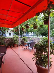 un patio con sombrilla roja, mesas y sillas en Vizitori Hotel, en Gonio