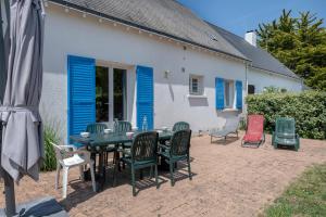 a patio with a table and chairs and blue shutters at Vacances paisibles tout près de l'océan in Piriac-sur-Mer