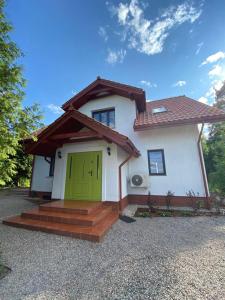 Dom Biały, willa nad jeziorem في Gawrych Ruda: منزل أبيض صغير مع باب أخضر