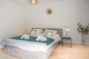 una camera da letto con un letto grande con lenzuola e cuscini bianchi di LE COCON TRESUM - Lac, Vieille ville, Garage ad Annecy