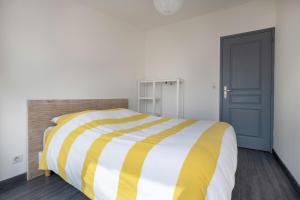 um quarto com uma cama listrada em amarelo e branco em Escapade au Croisic! em Le Croisic