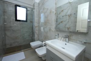 een badkamer met een wastafel, een toilet en een spiegel bij Hotel Roalb in Vlorë +29 foto's