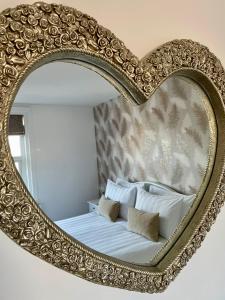 a mirror with a heart shaped frame over a bed at Apartment 33 Lytham in Lytham St Annes