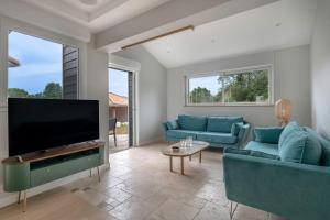 ein Wohnzimmer mit blauen Sofas und einem Flachbild-TV in der Unterkunft Maison avec piscine pour 8 adultes - 2 enfants in Saint-Père-en-Retz