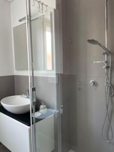 uma casa de banho branca com um lavatório e um chuveiro em SUITE DE ROLANDIS CirOO5005OO199 em Asti