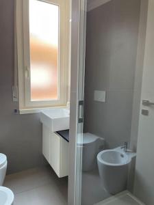 uma casa de banho branca com um lavatório e um WC em SUITE DE ROLANDIS CirOO5005OO199 em Asti