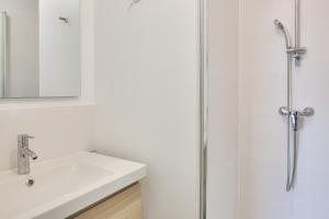 ein weißes Bad mit einem Waschbecken und einer Dusche in der Unterkunft Calme, detente et decouvertes en famille in Plobannalec-Lesconil