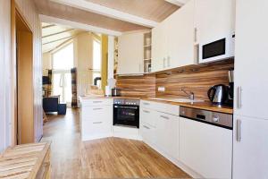 a kitchen with white cabinets and a wooden floor at Wellnesshaus Pappelhaus in Bliesdorf