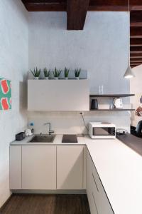 una cocina blanca con fregadero y 2 plantas en Rosa Luxury Apartment en Verona
