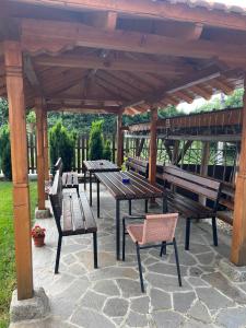 un grupo de mesas de picnic y sillas bajo un pabellón en Стаи за гости - Къща ТОНЧЕВИ en Kalofer