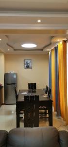 Un comedor con mesa y sillas y cortinas. en Jacaranda Gardens Furnished Apartments, en Nairobi