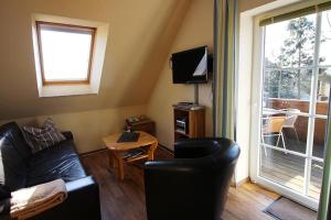 ein Wohnzimmer mit einem schwarzen Ledersofa und einem TV in der Unterkunft Gänseblümchen in Bliesdorf