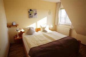 Schlafzimmer mit einem Bett mit weißer Bettwäsche und einem Fenster in der Unterkunft Gänseblümchen in Bliesdorf