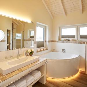 La salle de bains est pourvue d'une grande baignoire et d'un grand miroir. dans l'établissement Luxuswellnesshaus Krabbe, à Bliesdorf