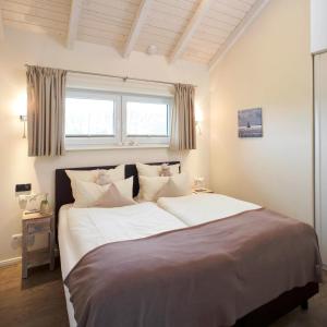BliesdorfにあるLuxuswellnesshaus Bootshusのベッドルーム1室(大型ベッド1台、白いシーツ、枕付)