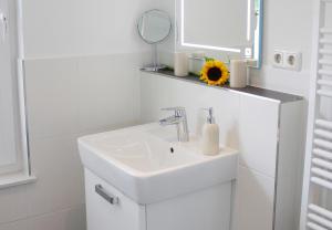 a white bathroom with a sink and a mirror at Penthouse Parkblick in Grömitz