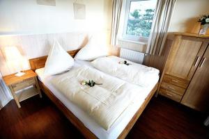 a bed with two white sheets and flowers on it at Wellnesshaus Austernperle in Bliesdorf