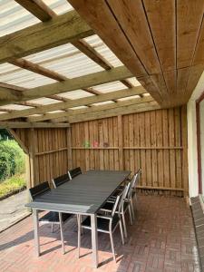 un patio con mesa, sillas y techo de madera. en Solhøj - a nice quite place just outside Billund en Billund