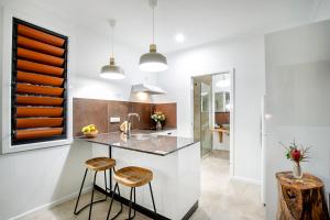 a kitchen with a counter and two stools at Airlie Beach Eco Cabins - Adults Only in Airlie Beach