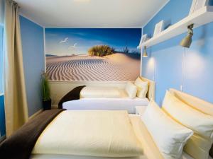 2 Betten in einem Zimmer mit einem Wandbild einer Wüste in der Unterkunft tohuus in Grömitz