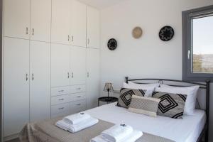 a bedroom with white cabinets and a bed with towels at Naxos King Villa in Galanádhon