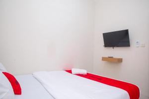 a white room with a bed and a flat screen tv at RedDoorz Syariah near Universitas Mercu Buana Kampus 2 Yogyakarta in Yogyakarta