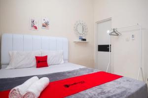 a bedroom with a white bed with red pillows at RedDoorz Syariah near Universitas Mercu Buana Kampus 2 Yogyakarta in Yogyakarta