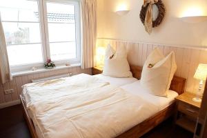 Una cama con sábanas blancas y almohadas en un dormitorio en Wellnesshaus Jacobsmuschel, en Bliesdorf