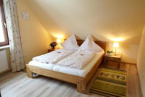 Schlafzimmer mit einem Bett mit weißer Bettwäsche und Kissen in der Unterkunft Traumgarten in Harmsdorf
