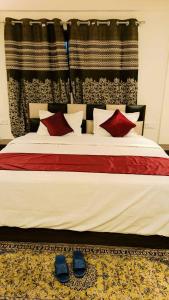 a bed with red and white pillows and a pair of shoes at Hotel Saima in Srinagar