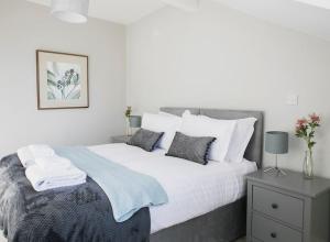 a white bedroom with a large bed with pillows at Valley Road, Fabulous 4 bedroom house in Harrogate