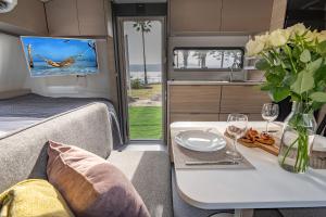 Caravana con mesa y TV en la pared en Dream Caravan's - קרוואנים מושלמים למשפחות בחוף כורסי בכינרת, en Ein Gev