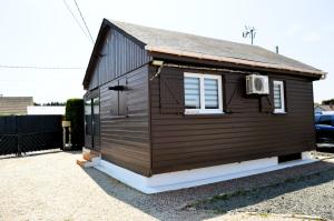 a tiny house with a window and a roof at Le Chalet à Hub - extérieur, proche de la plage in Asnelles