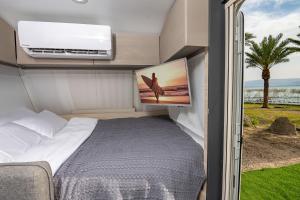 1 dormitorio en una cabaña con cama y ventana en Dream Caravan's - קרוואנים מושלמים למשפחות בחוף כורסי בכינרת, en Ein Gev