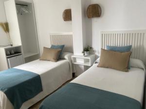 two beds in a room with blue and white at Hostal Andalucia in Nerja