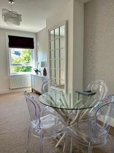 una sala da pranzo con tavolo in vetro e sedie di Apartment 33 Lytham a Lytham St Annes