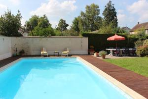 een zwembad in een achtertuin met een tafel en stoelen bij L'Alisier Chantant in Bourron-Marlotte