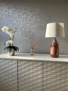 een witte dressoir met een lamp en bloemen erop bij Apartment 33 Lytham in Lytham St Annes