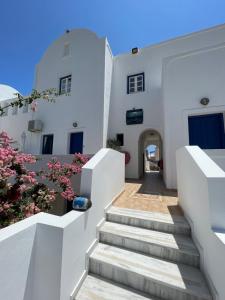 uma escadaria que leva a um edifício com flores cor-de-rosa em Leonidas Apartments em Kamari