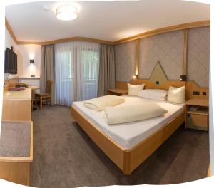 una camera da letto con un letto grande e una scrivania di Hotel Auffacherhof a Wildschönau Altre 94 foto